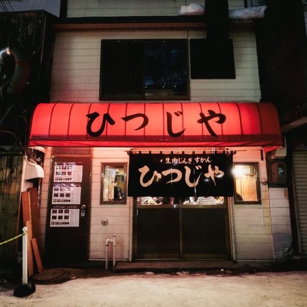 札幌すすきのの賑やかなメインストリートから一歩入った路地裏に、「ひつじや」は静かに佇んでいます。真っ赤なテント看板に書かれた「ひつじや」の文字と、年季の入った素朴な佇まいが、この店が積み重ねてきた歴史と、飾らない本物の味を物語ります。