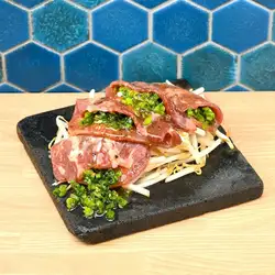 Grilled beef tongue with green onions and salt on a lava stone