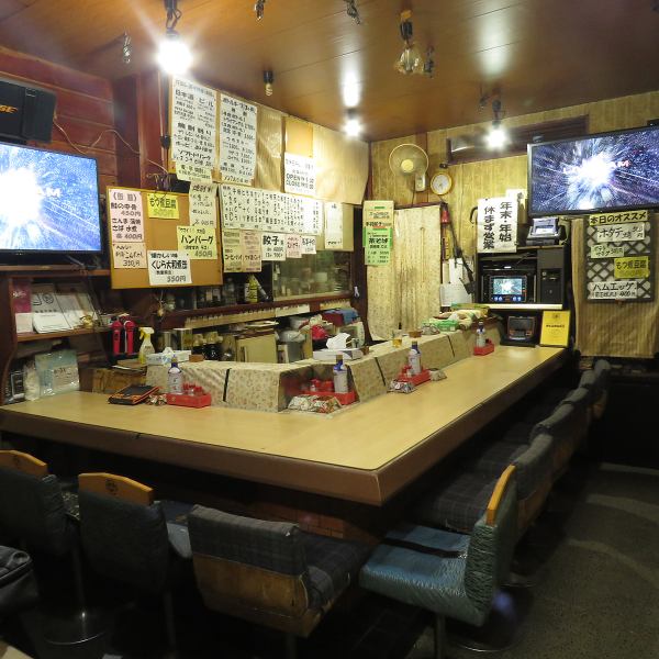 木の温もりを感じるカウンター席で、常連さんとの会話も弾むアットホームな空間。ゆったりくつろげるお座敷も完備し、グループ利用にも最適。壁一面の手書きメニューと提灯の灯りが懐かしさを演出します。