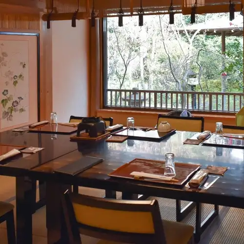【椿の間(椅子席)】<定員:8名様><特徴:三宜庵(茶室)や紅葉と椿の眺めが良いお部屋です。>秋には真っ赤に色付いた紅葉をお楽しみいただけます。また、光沢のあるグリーンの葉が特徴の椿も。大きな窓から見える景色を眺めながらお召し上がりになるお食事はまた格別です。落ち着いた空間でごゆっくりお過ごし下さい