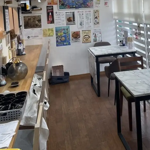 【入って右手はテーブル＆カウンター】厨房の活気が伝わるカウンター席と、2名様掛けテーブルをご用意。ウッド調×大理石風の内装は清潔感があり、女性のお一人様やランチ利用も快適に過ごせます。ＷｉＦｉ完備で動画を見ながらの食事もOK。仕事帰りのサク飲みや遅めの夕食利用も大歓迎です。