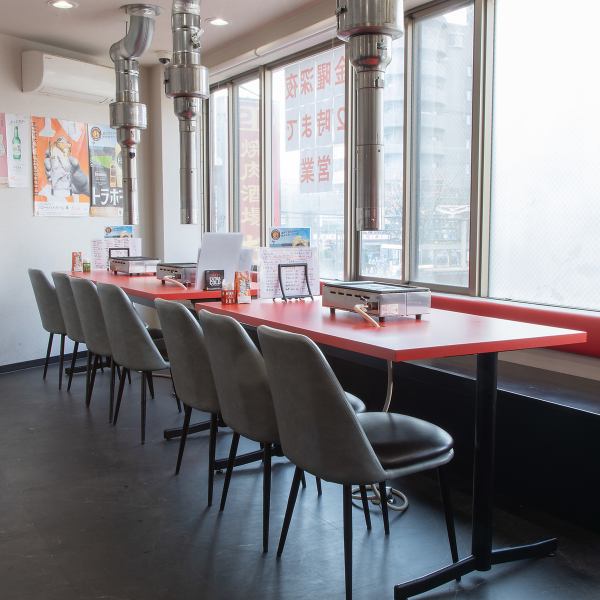 ゆったり座れるテーブル席は、グループ利用や宴会にぴったり！各席にグリルと排煙設備が整っているため、快適に焼肉を堪能できます。赤を基調とした空間は活気があり、女子会や会社帰りの集まりにも最適。ランチタイムには窓からの自然光も入り、明るく開放的な雰囲気です。