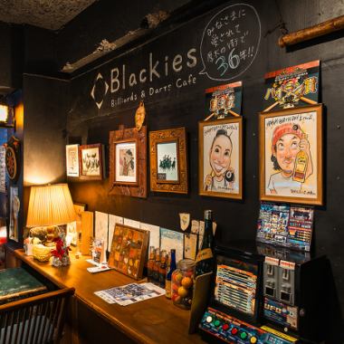 The inside of the store is finished entirely in black, with a long counter made of a single board that has been welcoming customers since its founding, box seats with large antique trunks as tables, and paintings by Balinese artists that give off a tropical atmosphere. There are many individualities that come together in a mysterious way, such as the walls lined with paintings drawn by little artists (customers' children).