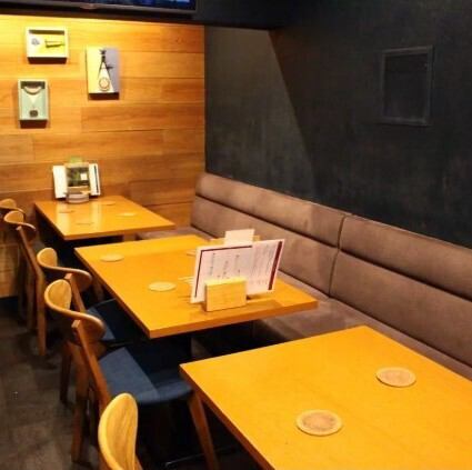<p>木目調のテーブルと壁が優しく迎える、落ち着いた空間。メニューとコースターが整えられた席に座れば、ゆったりとした時間が流れ出す。静かに語らい、食事を楽しむのにぴったりな、心安らぐひとときがここにあります</p>