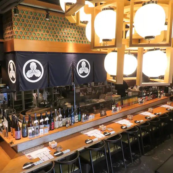【吧台座位:成人专属的优质座位】我们的吧台座位深受下班后小酌一杯、约会,甚至是独自用餐者的喜爱。在轻松舒适的氛围中享用九州美食和正宗烧酒。您还可以亲眼目睹我们的特色菜——萨摩烧鸡腿在炭火上烤制的过程,享受现场的乐趣。