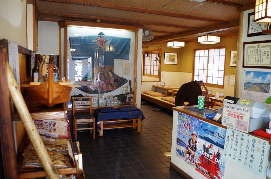 かつて大漁を祝い江島神社にお参りした際に着用したという伝統ある「眞祝」の貴重な最後の一着が飾られ、和の心意気を感じる店内。店舗向かいの丸だい本店にてお土産も買えます。