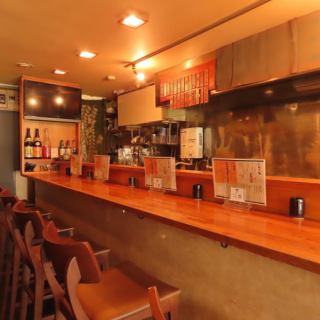 木の温もり溢れる「串揚げ 万雷」のカウンターは、職人の技を間近で愉しめる特等席。目の前で一本ずつ丁寧に揚げられるライブ感は、まさに五感を刺激する贅沢です。揚げたて熱々の串がベストなタイミングで差し出されるのは、この席ならではの醍醐味。お一人様や大切な方と、上質な大人時間を過ごしませんか？