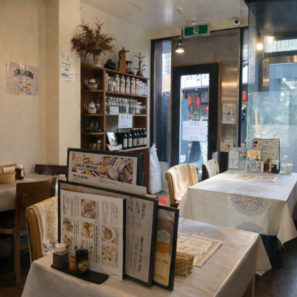 木の棚に並ぶボトルややわらかな自然光が心地よい店内。テーブル席はゆったり配置され、ランチからディナーまで落ち着いて過ごせる空間です。街中にありながら、ほっと一息つける居心地の良さが魅力。