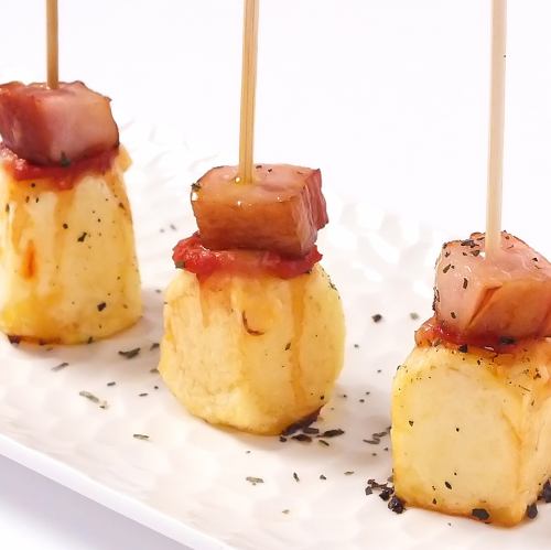 Oven-baked potatoes and pinchos of thick-sliced bacon