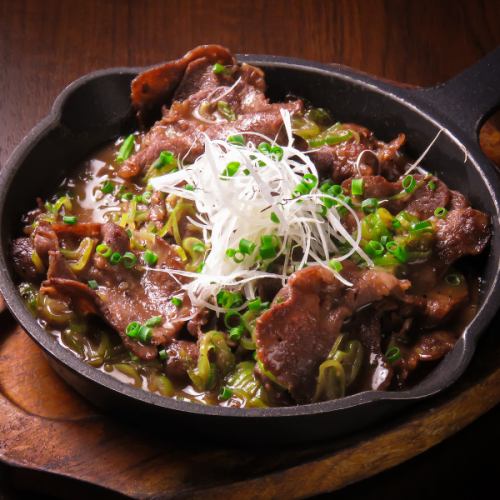 Grilled beef tongue and green onions on a hot plate