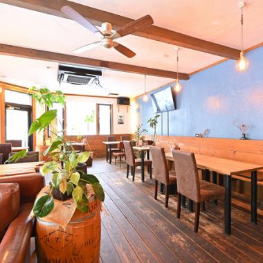 木の温もりとブルーの壁が調和する店内は、日常を忘れて寛げる開放的な雰囲気。ゆったりとしたソファ席や、陽光が差し込むテーブル席など、シーンに合わせてお選びいただけます。天井を回るシーリングファンや観葉植物が心地よい癒しを演出。お一人で、または大切な方と、穏やかなひとときをお過ごしください。