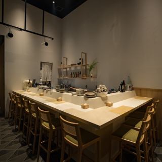 【焼貝とお酒 貝貝貝 ごひいき】【カウンター席：10席】白を基調としたカウンターのみの店内が特徴で、天井が高く開放感のある空間です。カウンター席は10席で目の前で新鮮な海鮮料理を楽しむことができます。シンプルで洗練された空間で、料理と会話をゆったりと楽しむことができる特別なひとときをお過ごしください。