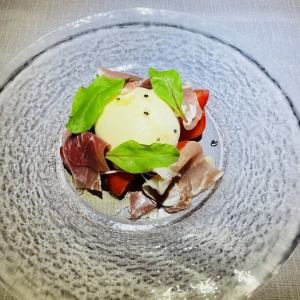 A plate of burrata cheese, ripe tomatoes, and prosciutto