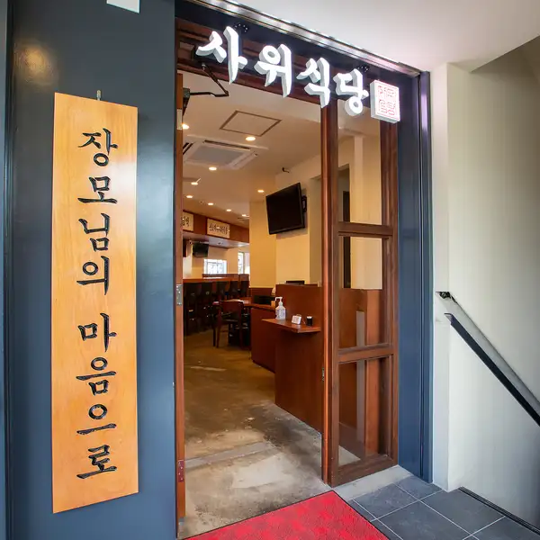 마치 서울의 길거리에 서 있는 듯한 세련된 외관이 인상적.큰 한국어 간판이 눈길을 끌고, 이국 정서 감도는 입구가 본고장의 맛에 대한 기대감을 높입니다.문을 열면 한국 요리의 세계가 펼쳐집니다.