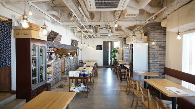 シンプルでありながらも温かみのあるデザインが魅力です。コンクリートの壁やむき出しの配管が、現代的なインダストリアルな雰囲気を醸し出しつつ、木のテーブルや椅子が心地よいアクセントになっています。自然光がたっぷり差し込む大きな窓からは開放感があり、訪れる人々が心地よく過ごせる設計になっております。