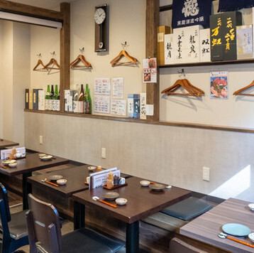 舒适的日式空间，充满木质的温暖气息。墙上贴满了清酒标签，营造出一种平静的氛围。宽敞的餐桌让您可以安心享受用餐和交谈，而不用担心旁边的人。宽敞的过道使通行更加方便。