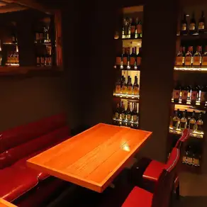 4～7名様のグループでのお食事におすすめのテーブル席。赤いソファと落ち着いた照明に囲まれ、気の合う仲間とゆったり会話を楽しめます。女子会や友人同士の飲み会、仕事帰りの集まり、少人数での忘年会にもぴったり。ワインと肉料理を囲みながら、いつもより少し特別なひとときをお過ごしください。