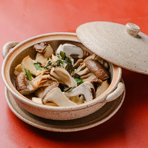 Steamed Hokkaido mushrooms in an earthenware pot with herb butter.