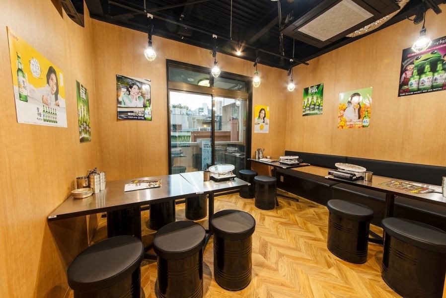 木目調の壁と床があたたかみを演出する親しみやすいテーブル席。ポスターが貼られた韓国食堂風のテイストで、どこか懐かしく気取らない楽しさが魅力。仲間でワイワイ食べたい時や、長居しながら語り合う飲み会におすすめです。