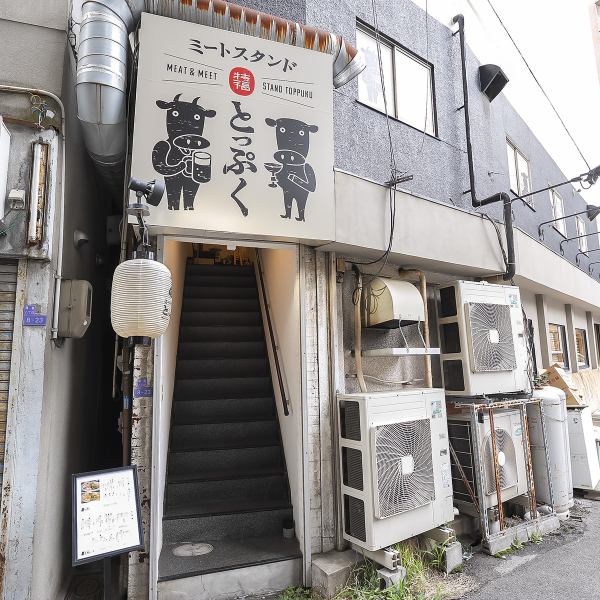 当店は、JR東西線新福島駅3出口から徒歩約4分の好立地に位置しています。ユニークな牛のイラストが描かれた看板が目印で、階段を上がると明るい店内が広がります。周囲の落ち着いた雰囲気の中で、友人や家族と楽しいひとときをお過ごしください。おしゃれな外観が皆様をお迎えします。