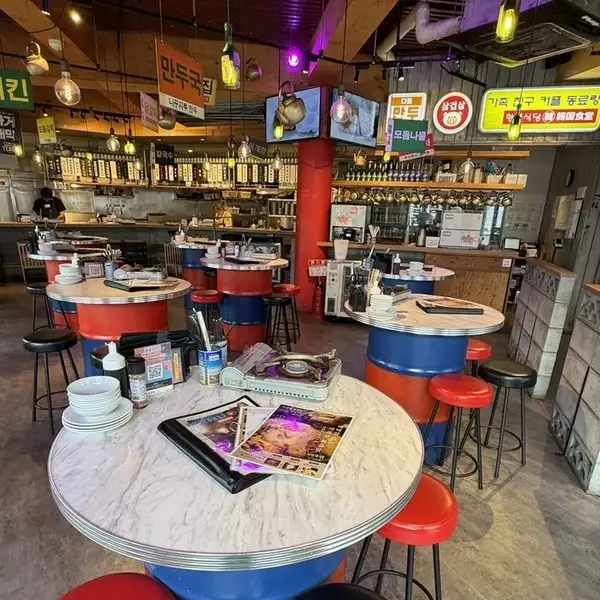 【まるで韓国の屋台街】ネオンサインに誘われ店内に入れば、見渡す限りのハングル語による案内板やカラフルな照明、ドラム缶に天板を載せたテーブルなど、ニューレトロな雰囲気の空間が広がります！まるで韓国旅行に訪れたようなトリップ感を楽しみながら、非日常的なひとときをお過ごしください♪
