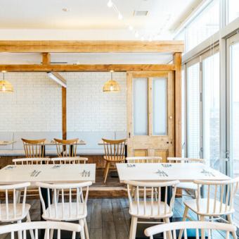大きな窓から自然光がたっぷりと差し込む店内は、明るく開放的な雰囲気です。木の温もりを感じるテーブルと椅子が配され、ゆったりと落ち着いてお食事をお楽しみいただけます。