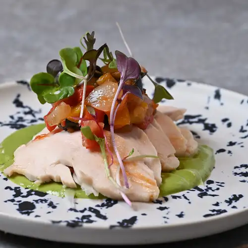 Low-temperature cooked Tajima chicken breast with caponata and chrysanthemum greens in a pesto sauce.