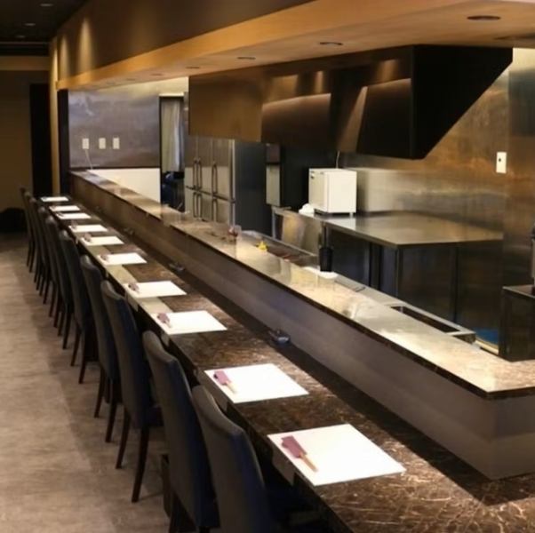 扉を開けると目の前に広がるのは、調理の様子を間近で見られるカウンター席です。シェフの鮮やかな手さばきや、鉄板から立ち上る香ばしい香り、食材が焼ける音など、五感全てで料理を楽しめる特等席。臨場感あふれるオープンキッチンのスタイルは、お食事の時間をより一層盛り上げてくれます。