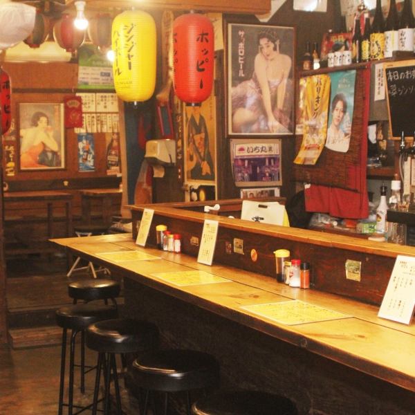 昭和レトロな雰囲気が漂う店内は、温かな灯りとカウンター席が心地よい落ち着きを演出。飾られたポスターや提灯が味わい深く、どこか懐かしい空気に包まれながらゆったり過ごせる空間です。