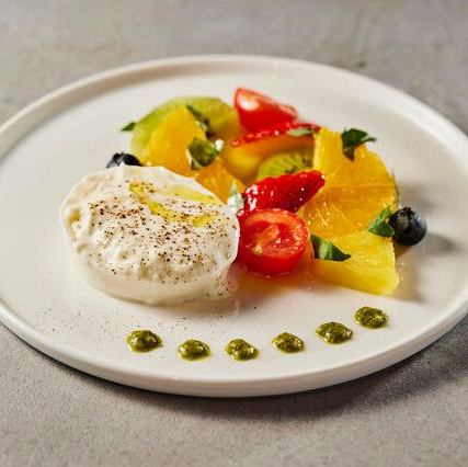 A platter of burrata cheese and fresh fruit