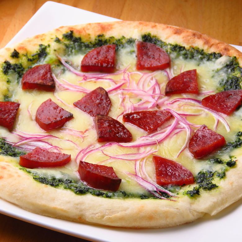 Homemade basil sauce pizza with raw ham and onions