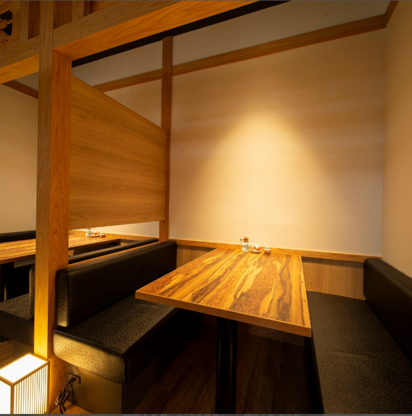 【小半個室】 上品な黒のベンチソファーにナチュラルな木目テーブルの半個室。天井は日本家屋らしい欄間で区切られています。天井と地面からの間接照明が陰影を作り、よりリラックスしていただけるよう演出します。きらくは新大阪すぐのホテル直結なので、ゲストの送迎や宿泊にも便利。カジュアルな接待空間としても◎ 