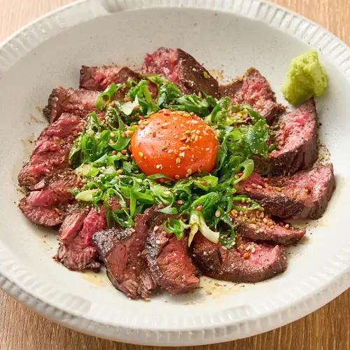 Beef skirt steak grilled over straw, topped with egg yolk