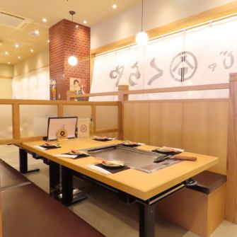 活気に満ちた広々とした店内は、全席に鉄板を完備しており、お客様ご自身で焼く楽しみと出来立ての熱々を味わう楽しさで賑わいます。木目調のテーブルと明るい照明が、カジュアルで居心地の良い空間を演出。様々なシーンでワイワイと盛り上がれる空間です。本格的なもんじゃ焼きを当店でぜひお楽しみください♪