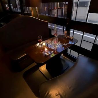 【ソファーテーブル席:5名様×2卓】上質なバル空間で女子会や各種宴会を楽しむ。バーカウンター前のテーブル席は、ゆったりとくつろげるソファー席をご用意。幾何学模様のガラス窓が目を引くおしゃれな窓際席は、女子会などの宴会にぴったりです。