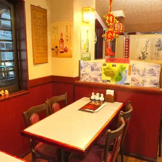 【テーブル】老若男女に愛される当店は、居心地の良いアットホームなテーブル席をご用意。赤い縁取りのテーブルとレトロな椅子は、懐かしい中華屋の雰囲気。壁の紹興酒ポスターや天井の赤い提灯が賑やかさを演出し、家族連れからお一人様までリラックスして本格的な中華を楽しめます。