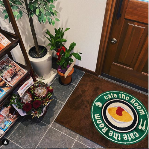 在木材温暖的入口处，带有商店徽标和观叶植物的垫子将欢迎您的光临！