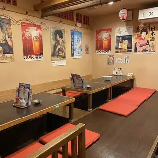這是一個架高的榻榻米休息區，您可以在這裡脫掉鞋子，舒適地放鬆身心。牆上裝飾著手寫的菜單和復古海報，營造出溫馨宜人的氛圍，非常適合與好友聚會。