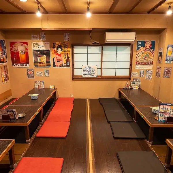 靴を脱いでゆったりとくつろげる小上がりのお座敷席です。壁には手書きのおすすめメニューやレトロなポスターが貼られており、親しい仲間との飲み会にぴったりのアットホームな空間です。