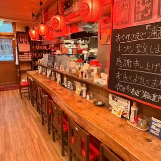 這家熱鬧休閒的居酒屋（日式酒吧）內部燈光溫暖，紅色的招牌和寫著「蔥」（Negi）的燈籠照亮了整個空間。飽經歲月洗禮、極具特色的 L 形木製櫃檯旁擺放著紅色圓形凳子，面前的展示櫃和廚房營造出熱鬧的氛圍。餐廳內張貼的菜單和調味品營造出輕鬆、溫馨的昭和時代復古氛圍，讓人感到舒適自在。