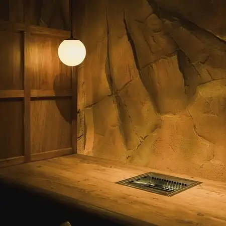 【1階／2名様用・半個室カウンター】2名席を10卓ご用意。木の温もりに包まれて、おひとりでのお食事やおふたりの会食をゆっくりとお楽しみください。1階は禁煙です。