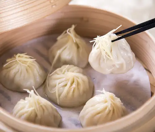 A rich, flavorful soup overflows! Homemade, hand-wrapped xiao long bao.