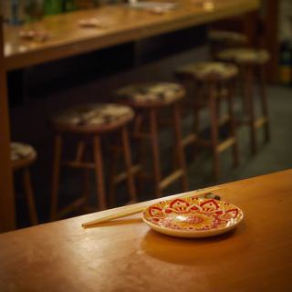 一歩足を踏み入れた瞬間、静けさと香ばしい香りに包まれる。全席カウンターの店内では、料理人が目の前で藁焼きの調理を披露。立ちのぼる煙、火の音、香ばしい香り──五感を通して料理と向き合える“体験の場”です。