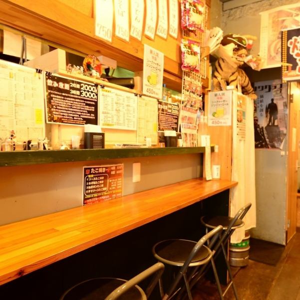 通り沿いの焼き場から香ばしい匂いが漂う、レトロな雰囲気のたこ焼き屋。カウンター席に座れば、横で焼き上がるたこ焼きを眺めながら、友達や家族と肩を並べてワイワイ楽しめます。壁一面のポスターが懐かしさを演出し、どこか温かい居心地の良さも魅力です。