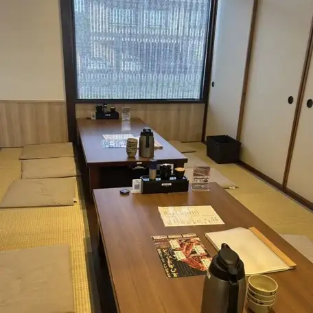 <p>畳の温もりを感じられる広々とした座敷席が完備されており靴を脱いで寛げる空間となっています。木製の低いテーブルとふんわりとした座布団が配置されており小さなお子様連れのご家族でも安心して利用できるレイアウトが魅力です。障子や和風のインテリアが配置され落ち着きのある和の時間を演出します。</p>