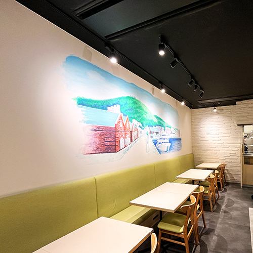 店内奥の白壁には函館ベイエリアの風景が...実はこれ函館本社のデザイン担当が直接壁に描いたものなのです！東京にいながら函館の港と赤レンガの風景を眺めながら函館の味を楽しむ---これが当店の醍醐味です♪