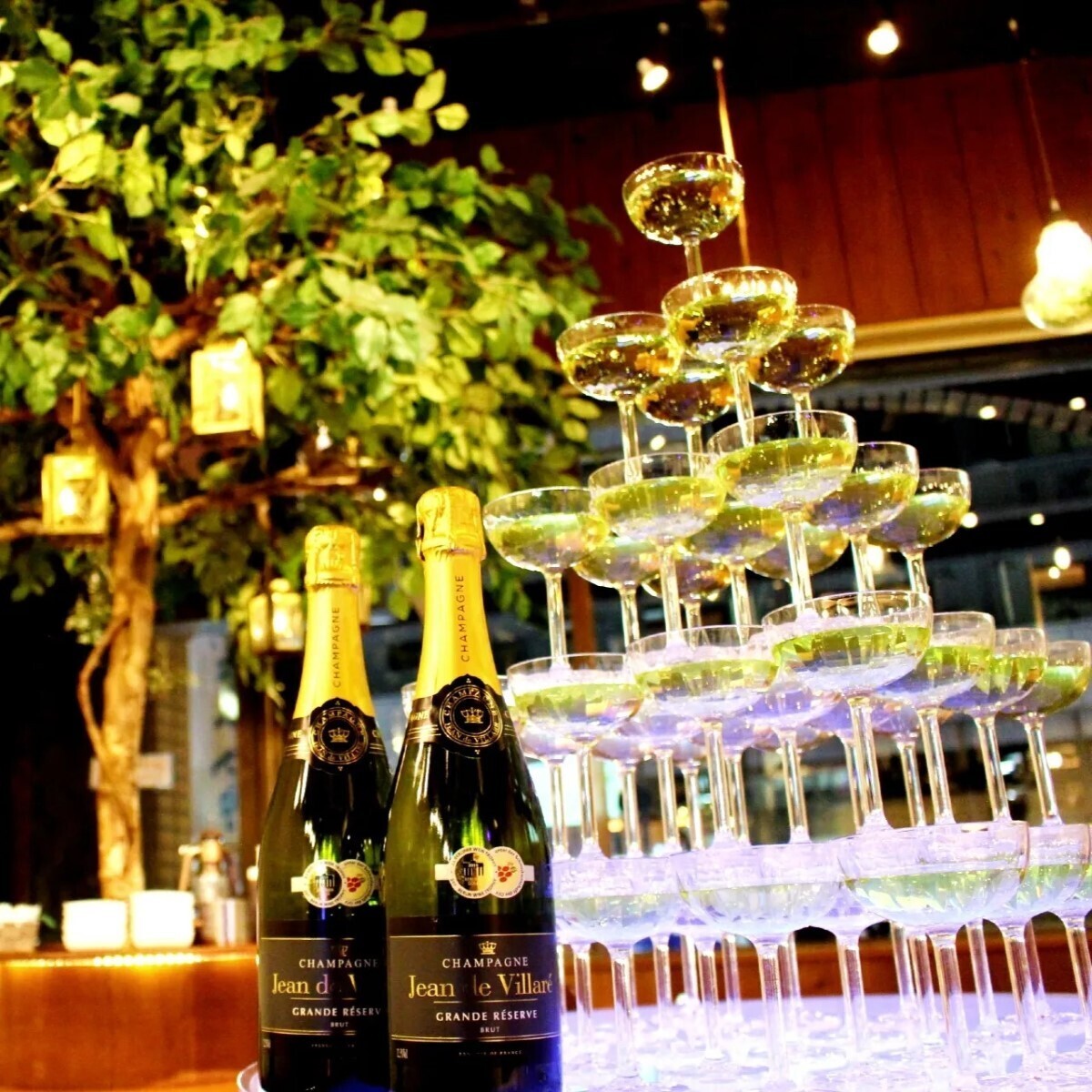 A champagne tower and champagne bottles set up in front of a wooden sculpture (Shibuya Garden Space Dogenzaka store)