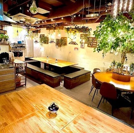 渋谷ガーデンスペース道玄坂店の店内。木のテーブル席と壁面の映像、天井の緑