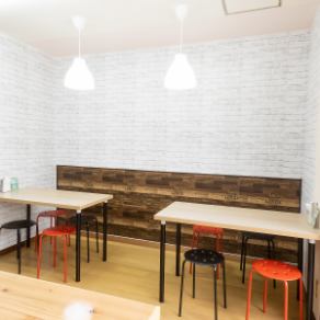 这张可供四人就餐的餐桌位于一个干净整洁的空间，白色砖纹壁纸给人一种明亮的感觉。现代的红黑相间凳子增添了一抹亮色，营造出一个休闲舒适的空间，适合各种场合，例如与朋友共进午餐、女孩们的夜晚聚会或与家人共进下午茶。