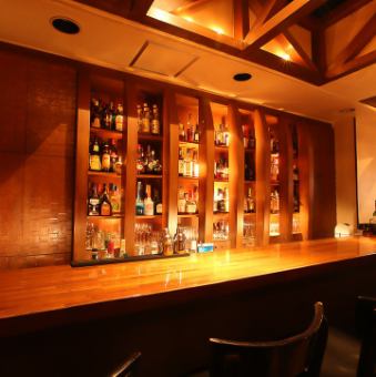 【カウンター席】カウンター正面に構える、凝ったつくりの棚の中には年代物のウイスキーやワインなどが並んでいます。バーテンダーが振舞うお酒とこだわりのお料理をお楽しみください。
